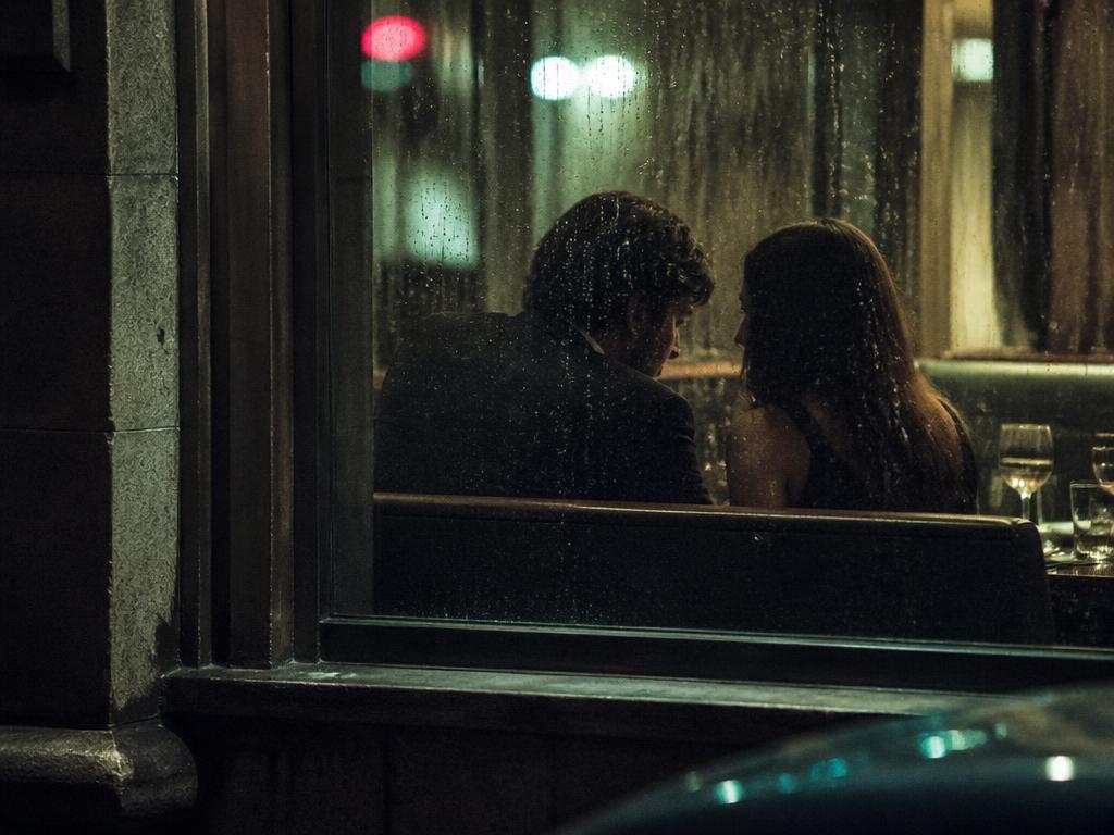 Beweisfoto: Paar in einem Restaurant bei nächtlicher Observation durch ein regennasses Fenster