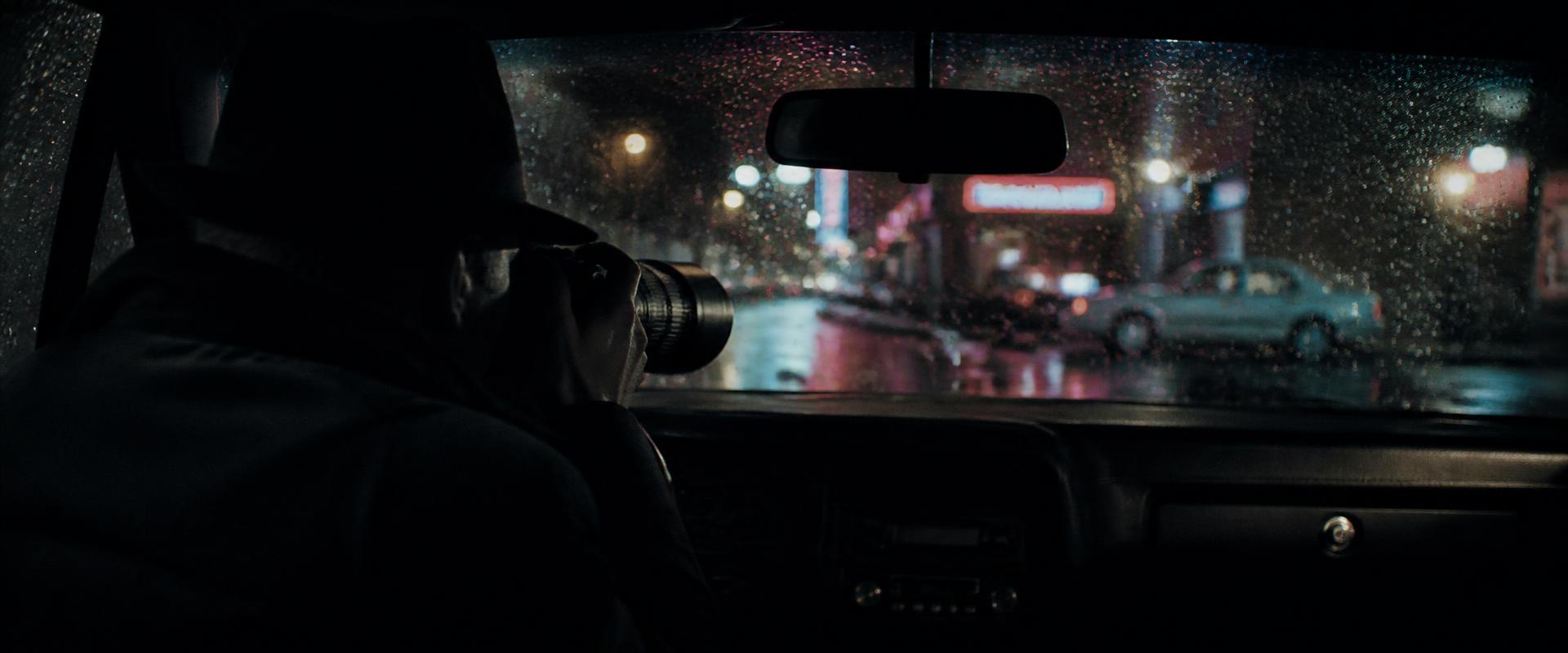 Privatdetektiv mit Teleobjektiv bei verdeckter Observation aus dem Auto
